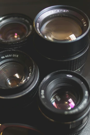 a group of camera lenses sitting on top of a table, slight lens glare, looking down on the camera, looking into camera