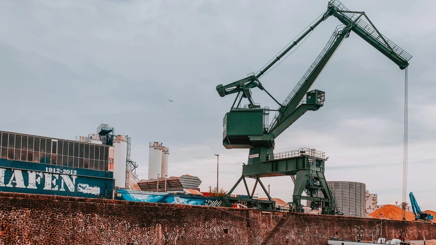 a large crane sitting on top of a cement wall, by Andries Stock, pexels contest winner, utilitarian cargo ship, high quality product image”, 1980s photo, scrapyard architecture