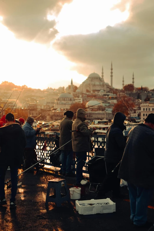 a group of people standing on top of a bridge, by Niyazi Selimoglu, happening, mosque, winter sun, city views, slide show