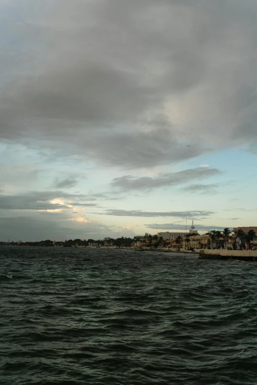 a large body of water under a cloudy sky, a picture, happening, dakar, late summer evening, small port village, multiple wide angles