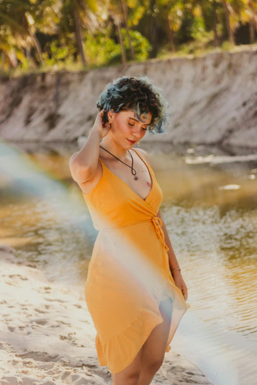a woman standing on a beach next to a body of water, wavy hair yellow theme, on a riverbank, profile image, show