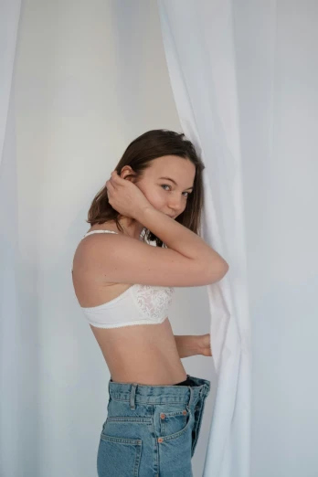 a woman standing in front of a curtain, white bra, photo of young woman, on a pale background, shot with sony alpha