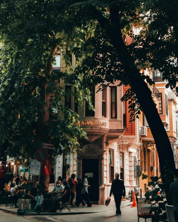 a group of people walking down a street next to tall buildings, pexels contest winner, art nouveau, sitting under a tree, istanbul, background image, lgbtq