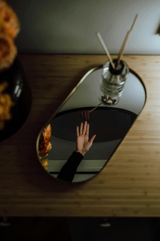 a person taking a picture of themselves in a mirror, a still life, by Julia Pishtar, minimalism, silver platter, raised hand, warm moody lighting, ultrawide image