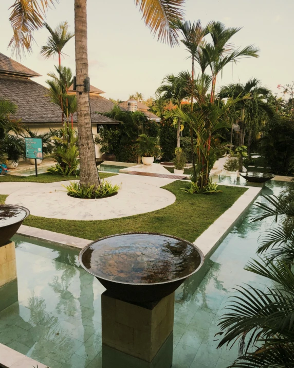 a couple of water fountains sitting on top of a lush green field, next to a tropical pool, dreamy vibe, thumbnail, courtyard