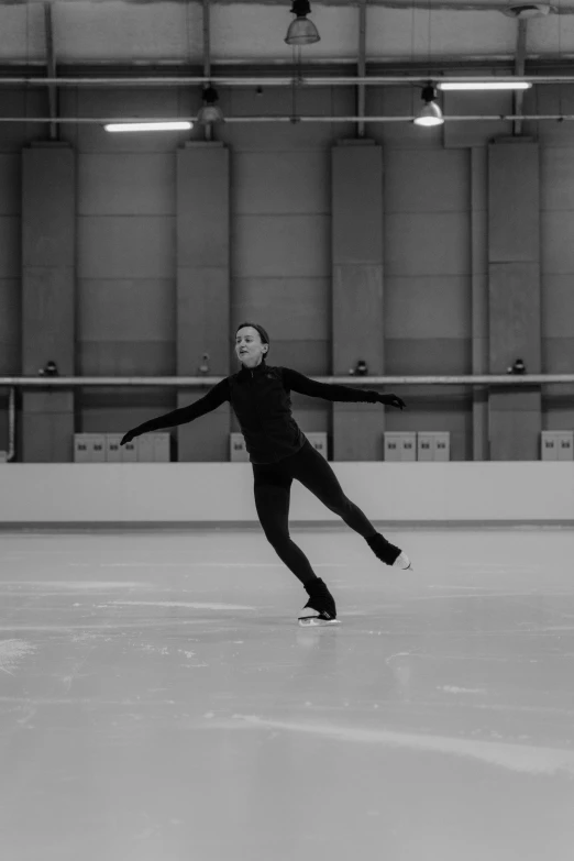 a black and white photo of a figure skating, inspired by Fei Danxu, unsplash, arabesque, low quality footage, wearing a tracksuit, looking happy, made of ice