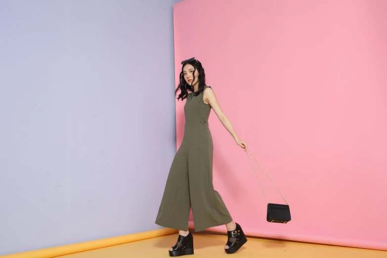 a woman standing in front of a pink and blue wall, olive green, jumpsuits, official product image, cut out