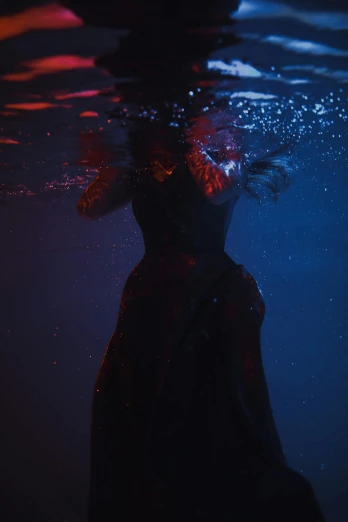 a person swimming under the water at night, inspired by Brooke Shaden, unsplash, renaissance, dark dress, red and blue black light, **cinematic, detail shot