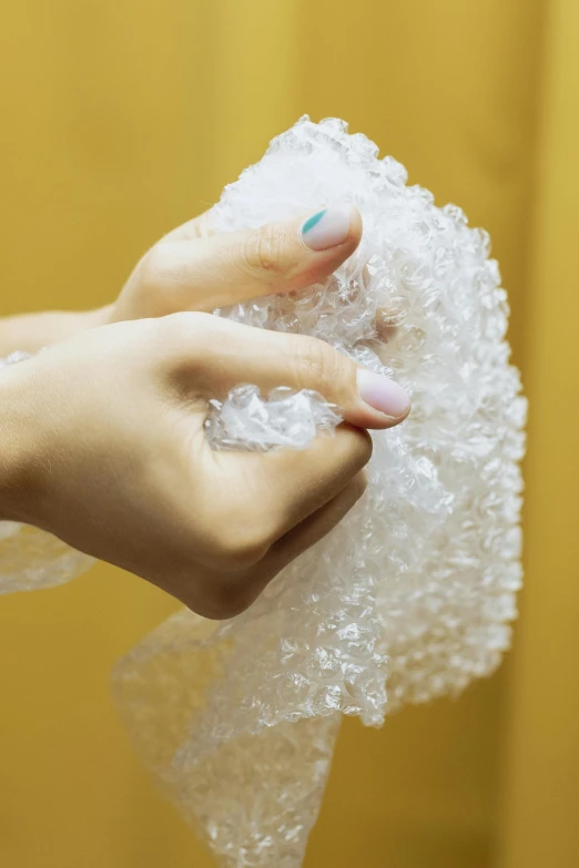 a person holding a piece of bubble wrap in their hand, bubbling skin, synthetic materials, curls, uncropped