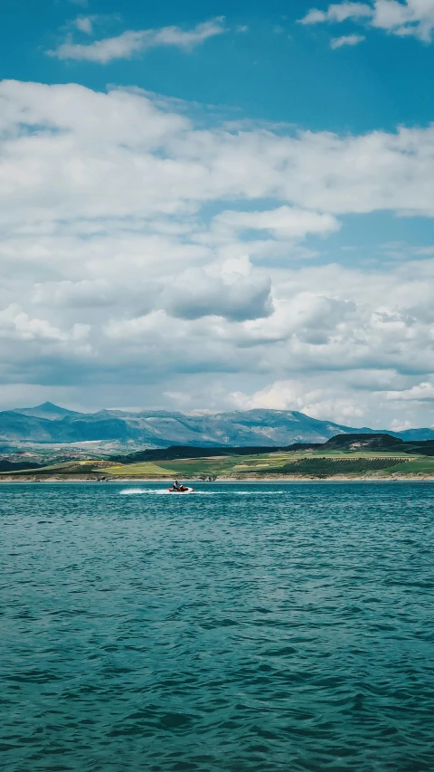 a large body of water with mountains in the background, by Andrew Allan, unsplash, hurufiyya, maryport, on a boat on a lake, thumbnail, high quality photo