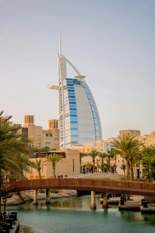 a bridge over a body of water with a building in the background, dau-al-set, dubai, minas tirith in the background, in a beachfront environment, lead - covered spire