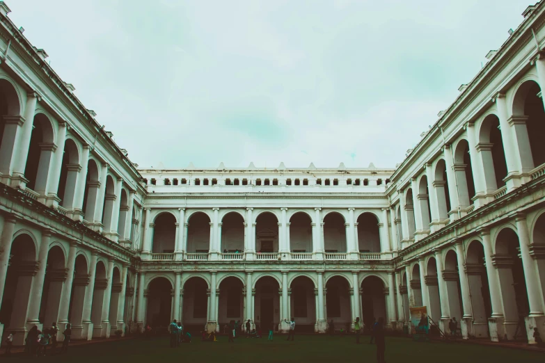 a group of people standing in a courtyard of a building, inspired by Mihály Munkácsy, pexels contest winner, bengal school of art, lawn, vast library, background image, lomography photo