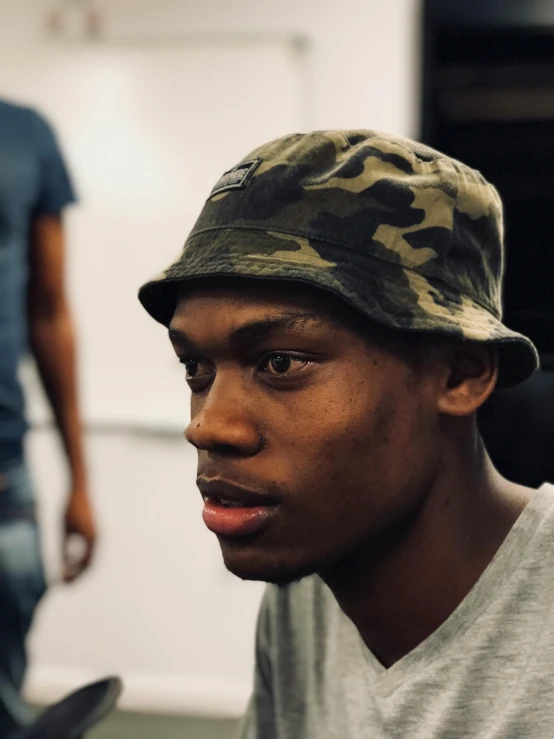 a close up of a person wearing a hat, featured on instagram, wearing camo, dave chappelle, black teenage boy, ( ( theatrical ) )