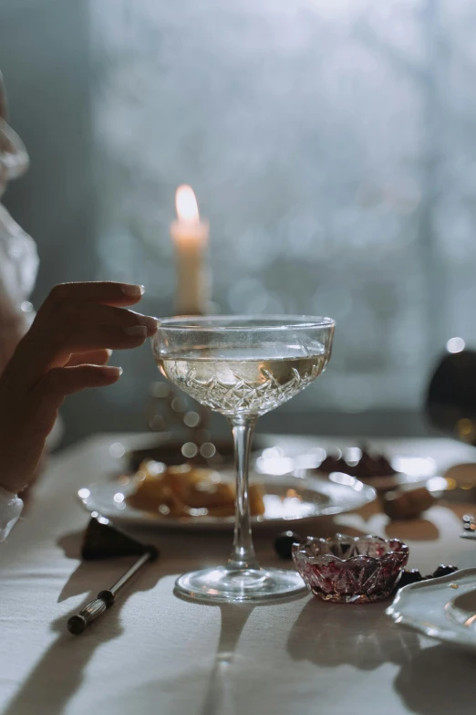 a woman sitting at a table with a glass of wine, inspired by Hedda Sterne, pexels, renaissance, champagne on the table, gif, dessert, ethereal bubbles