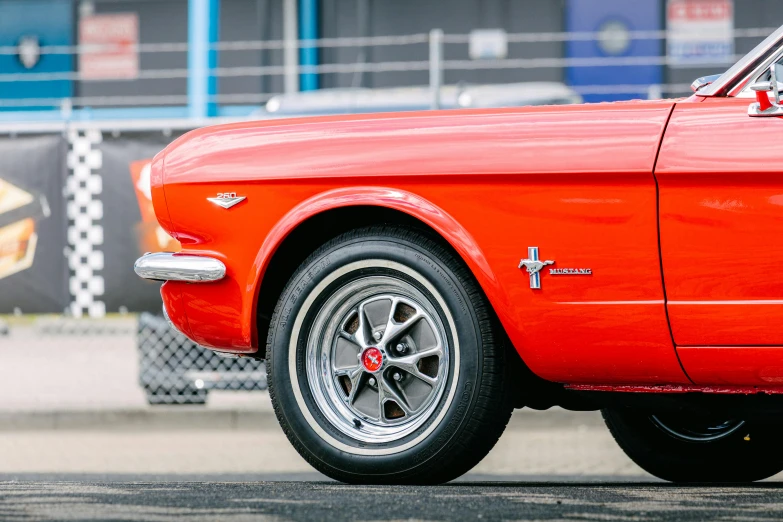 a red car parked in front of a building, by Jan Tengnagel, pexels contest winner, photorealism, mustang, detailed alloy wheels, profile close-up view, 🦩🪐🐞👩🏻🦳