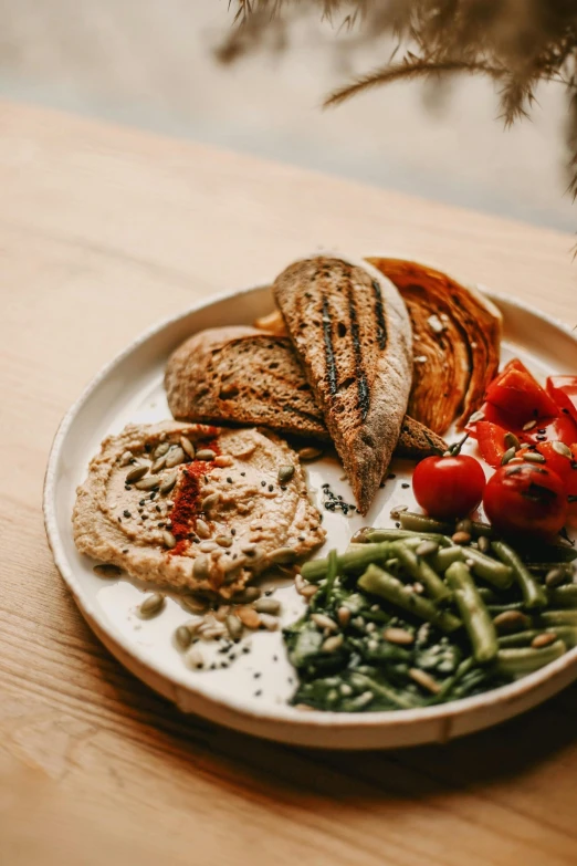 a plate of food on a wooden table, pexels contest winner, humus, beans, brown bread with sliced salo, veggies