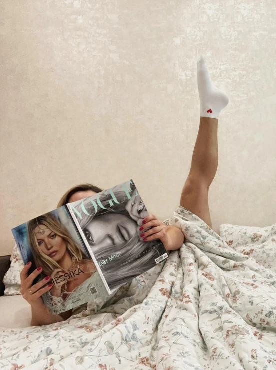 a woman laying in bed reading a book, an album cover, inspired by Elsa Bleda, trending on reddit, happening, wearing white tights, vogue magazine cover, wearing a hospital gown, anna nikonova aka newmilky