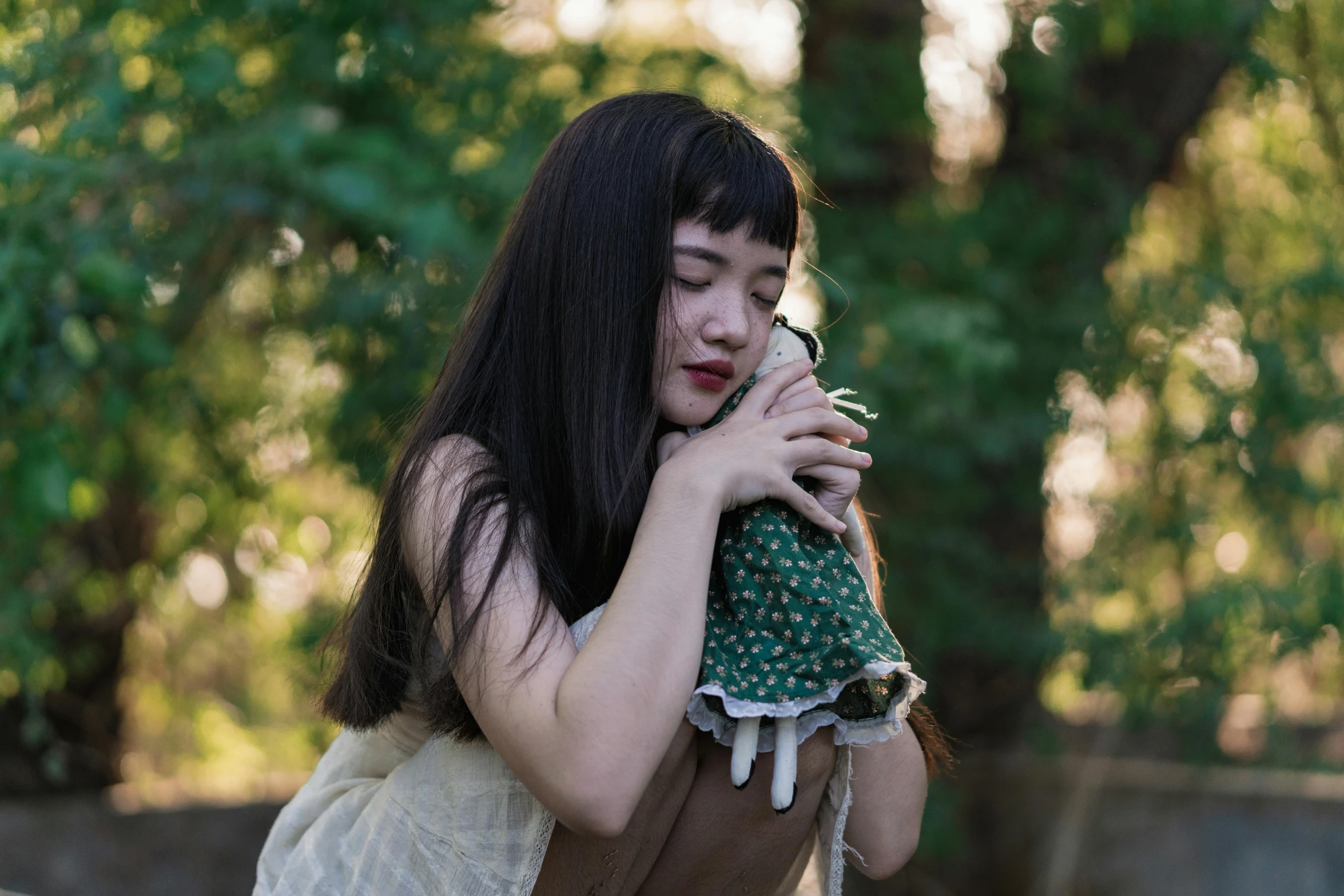 a woman holding a stuffed animal in her arms, an album cover, unsplash, renaissance, asian women, dark green, joey king, cottagecore