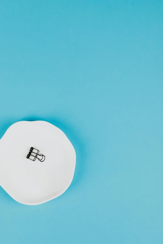 a white spoon sitting on top of a blue surface, by Nicolette Macnamara, trending on unsplash, minimalism, rubber stamp, ring, square, dish