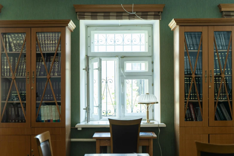 a table and chairs in front of a window, inspired by Illarion Pryanishnikov, unsplash, neoclassicism, small library, full frame image, located in hajibektash complex, green stained glass