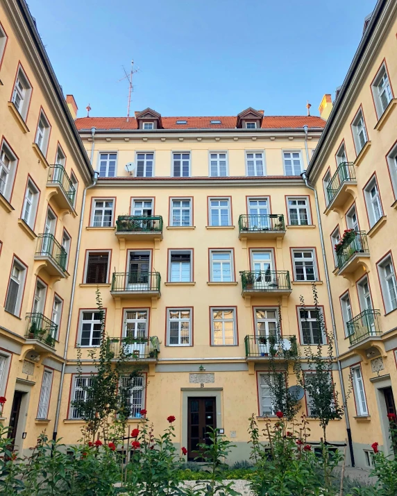 a yellow building with lots of windows and balconies, inspired by Albert Paris Gütersloh, pexels contest winner, berlin secession, courtyard, city apartment cozy calm, munich, green square