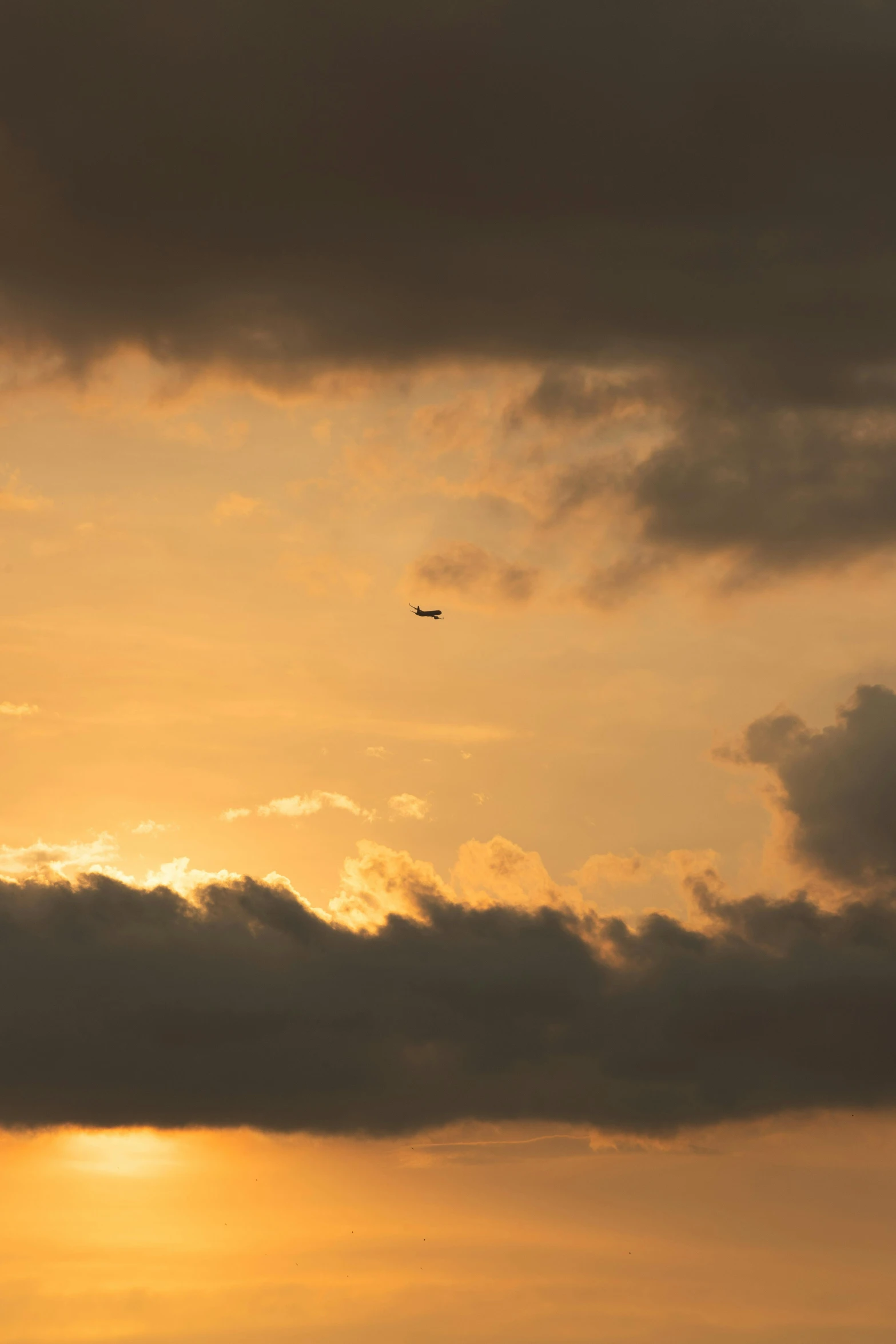 a large jetliner flying through a cloudy sky, by Jan Tengnagel, pexels contest winner, minimalism, real sunset, yellow, air support, brown