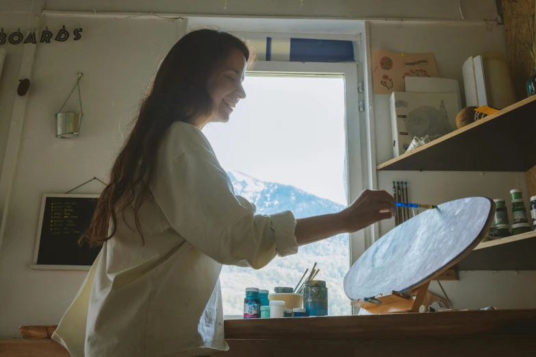 a woman that is standing in front of a mirror, a photorealistic painting, pexels contest winner, the sun reflecting on a window, in a workshop, looking happy, swiping brushwork