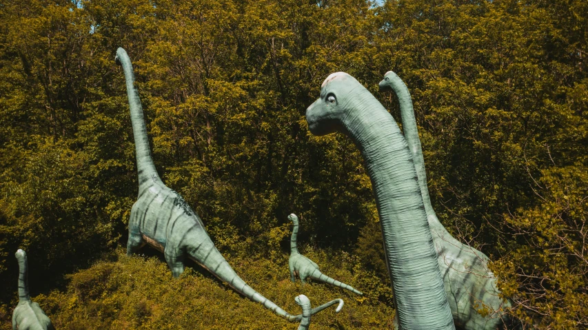 a group of dinosaurs that are standing in the grass, a statue, by Carey Morris, pexels contest winner, magic realism, very long neck, waving, avatar image, a high angle shot