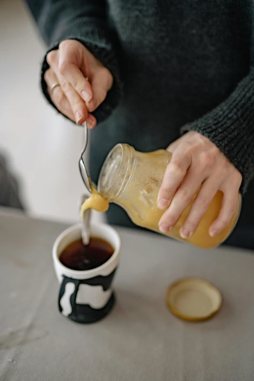 a person pouring something into a cup on a table, manuka, profile image, mustard, freezing