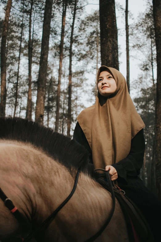 a woman riding on the back of a brown horse, by Basuki Abdullah, trending on unsplash, sumatraism, hooded cowl, square, beige, in the wood