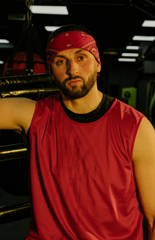 a man in a red shirt posing for a picture, inspired by Volkan Baga, rugged man portrait, wearing basketball jersey, dingy gym, production still