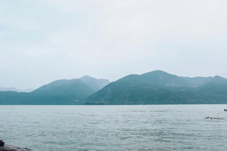 a large body of water with mountains in the background, inspired by Zhang Kechun, trending on unsplash, in hong kong, low quality photo, fan favorite, 4 k smooth