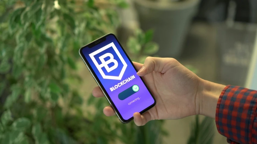 a person holding a cell phone in their hand, blockchain vault, next to a plant, square, thumbnail