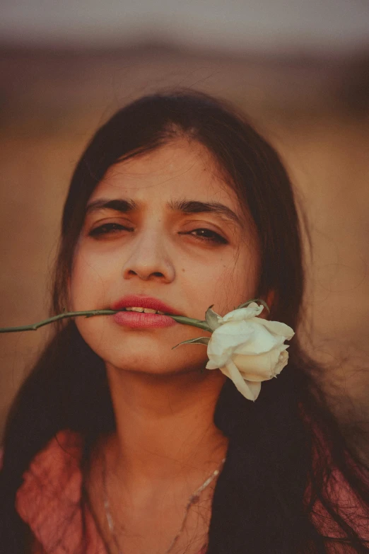 a girl with a flower in her mouth, an album cover, inspired by irakli nadar, pexels contest winner, provocative indian, gentle expression, teenager, grainy