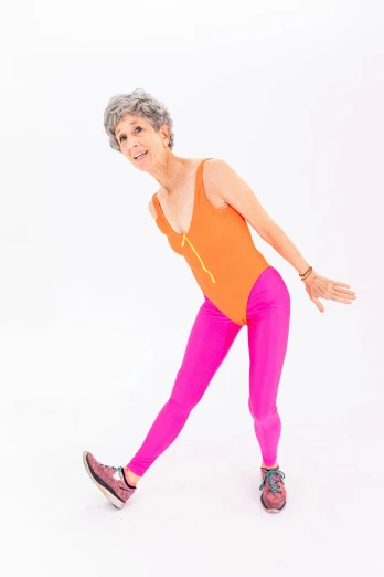 a woman in a bright orange top and pink leggings, by Pamela Drew, dribble, older woman, thin bodysuit, sarcastic pose, ap press photo