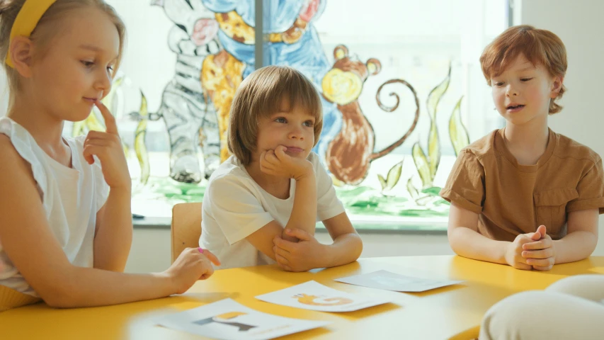 a group of children sitting around a yellow table