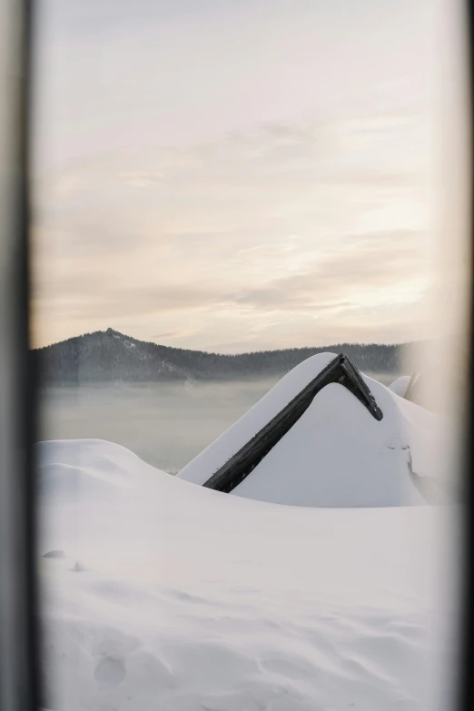 a snow covered roof is seen through a window, inspired by Einar Hakonarson, crater lake, blanket of fog, peak