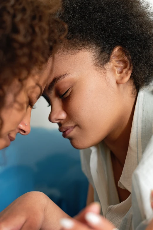 a couple of women laying on top of a bed, trending on pexels, renaissance, portrait of mournful, mixed-race woman, shy looking down, profile image