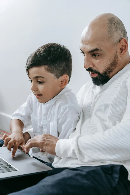 a man sitting next to a little boy on a laptop, arabic, gen z, thumbnail, father figure image