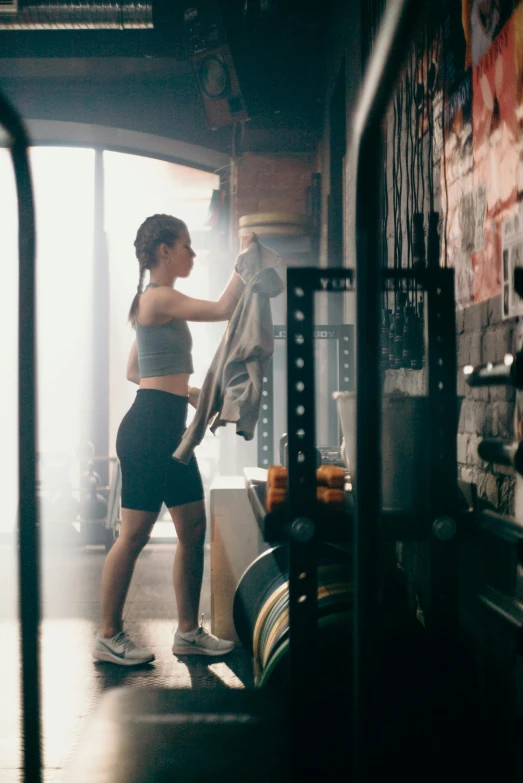 a woman holding a towel in a gym, by Daniel Lieske, pexels contest winner, bra and shorts streetwear, inspect in inventory image, morning glow, grit