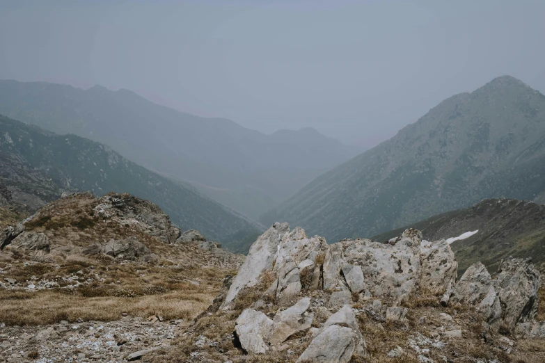 a large pile of rocks sitting on top of a mountain, an album cover, inspired by Zhang Kechun, unsplash contest winner, empty remote wilderness, grey, view, [ cinematic