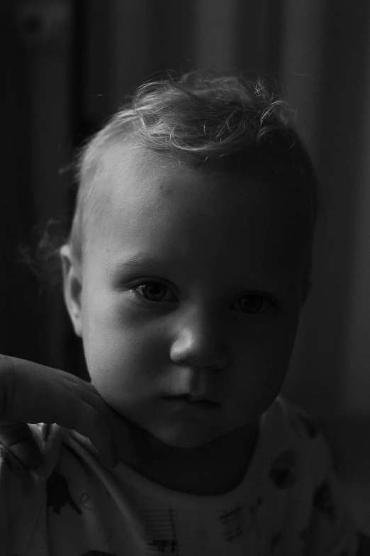 a black and white photo of a baby, inspired by Roy DeCarava, pexels contest winner, intimidating glare, underexposed lighting, medium format. soft light, sittin