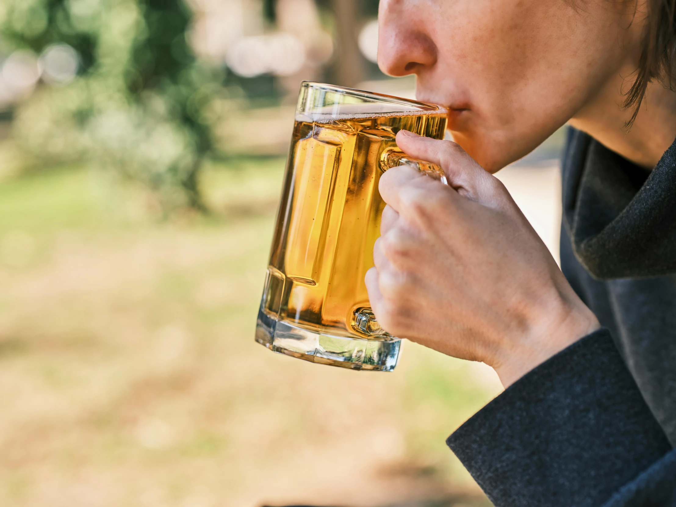 a woman is drinking a glass of beer, a screenshot, pexels contest winner, cider-man, close up shot from the side, al fresco, uncropped