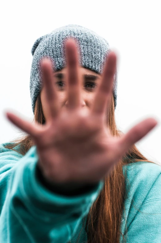 a woman making a stop sign with her hands, unsplash, antipodeans, wearing teal beanie, square, headshot, steep