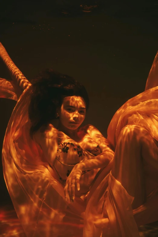 a woman sitting on top of a bed under a light, inspired by David LaChapelle, video art, orange and yellow costume, a woman floats in midair, still from a ridley scott movie, showstudio