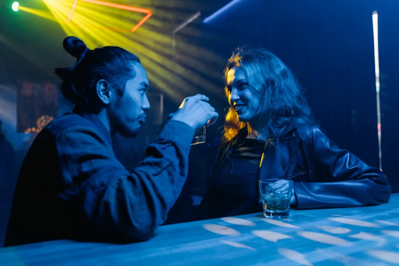 a couple of people that are sitting at a table, inspired by Nan Goldin, unsplash, nightclub, lee madgwick & liam wong, scene from live action movie, profile image