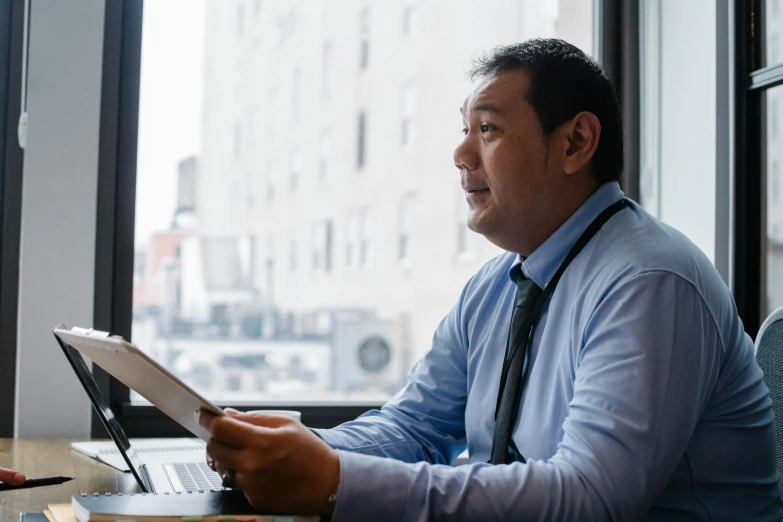 a man sitting at a table in front of a laptop computer, unsplash, shin hanga, next to a window, avatar image, professional closeup photo, asian origin