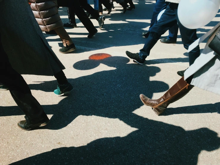 a crowd of people walking down a street, an album cover, by Niko Henrichon, trending on unsplash, long shadow, sun puddle, shows a leg, parade