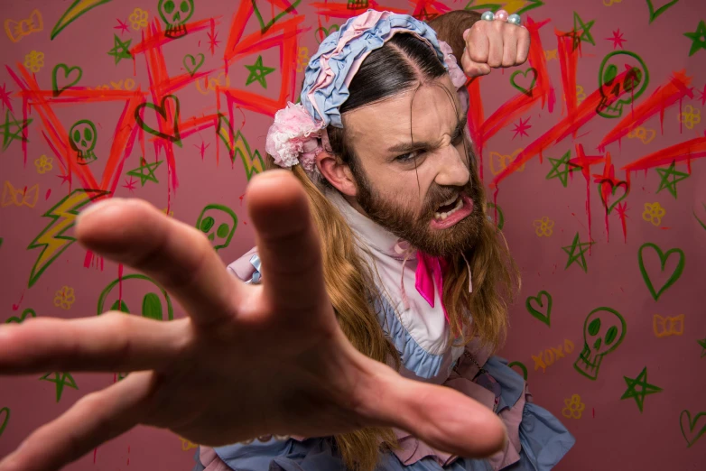 a man standing in front of a wall covered in graffiti, an album cover, inspired by Richard Dadd, transgressive art, belle delphine, tentacles beard, angry high moral sexy werewolf, hands down