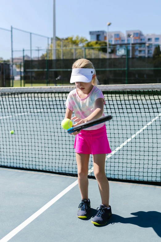 a little girl standing on top of a tennis court holding a racquet, neon visor, mid action swing, soft surfaces, nets